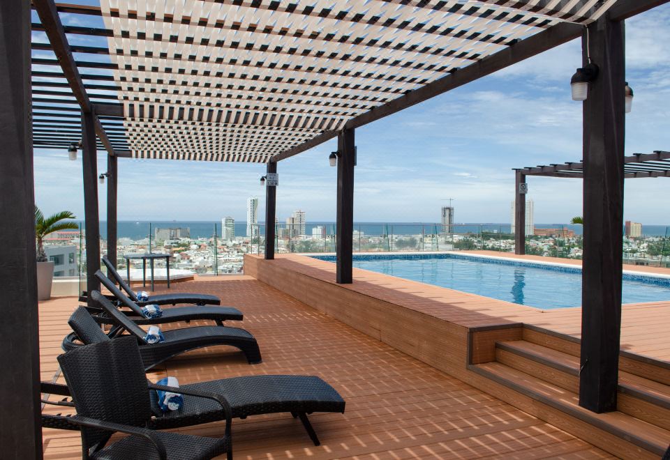 a rooftop patio with a swimming pool surrounded by lounge chairs , providing a relaxing atmosphere at Four Points by Sheraton Veracruz