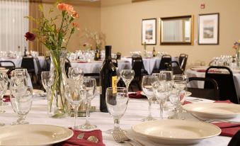 a well - set table with white plates , red napkins , and wine glasses is shown in a restaurant at The Landing Hotel