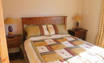 a well - decorated bedroom with a wooden bed , a nightstand , and a lamp , as well as a staircase in the background at The Loft