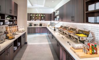a large kitchen with multiple food dispensers and a variety of dishes on display , including wine bottles and glasses at Hyatt Place East Moline/Quad Cities