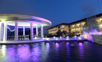 a beautiful nighttime scene of a modern building with purple lights reflecting in a body of water at The Singhasari Resort Batu