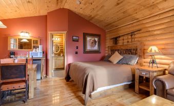 a cozy bedroom with wooden walls , a bed , and a bathroom in the background , lit by lamps at Zion Mountain Ranch