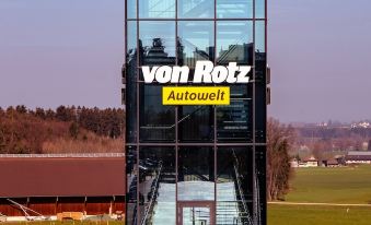 "a large glass building with the words "" hotel "" and "" hotel von rotz "" prominently displayed on it" at Self Check-in Hotel Von Rotz