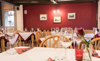 a restaurant with tables set for dining , wine glasses , forks , knives , and napkins on the tables at The Rose and Crown