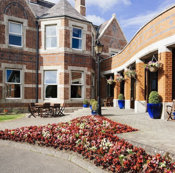 a brick building with a flower bed in front of it , creating a pleasant and inviting atmosphere at Brandon House Hotel