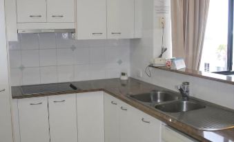 a kitchen with white cabinets , a sink , and a window with curtains , as well as a window near the window at Kings Row Apartments