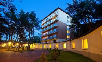 a modern apartment building with multiple floors and balconies lit up at night , surrounded by trees at Millennium Spa