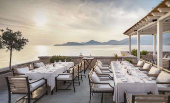 a restaurant overlooking the ocean , with tables and chairs set up for guests to enjoy a meal at Aman Sveti Stefan