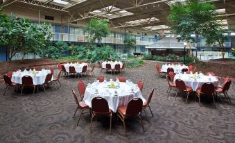 a large dining room with multiple round tables and chairs , set for a formal event at Ramada by Wyndham Clarion