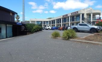 a parking lot with several cars parked in front of a large building , including a hotel at Jacksons Motor Inn