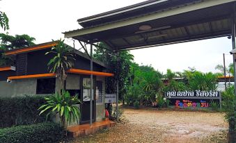 a small house with a green roof and an orange door , surrounded by a dirt field at Khun Naparn Resort