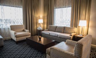 a living room with a couch , chairs , and coffee table is shown in front of windows at Brent House Hotel