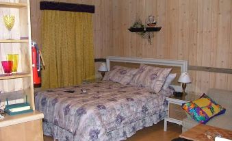a bed with a floral comforter is in a room with wooden walls and yellow curtains at Lamplight Inn