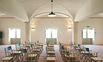a large , empty room with white walls and wooden floors , containing rows of empty folding chairs and tables at Sao Lourenco do Barrocal