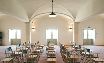 a large , empty room with rows of wooden folding chairs arranged in a circle , creating a seating area for a group of people at São Lourenço do Barrocal