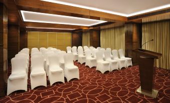 a large conference room with white chairs arranged in rows and a red carpet on the floor at Four Points by Sheraton Ahmedabad