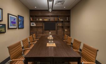 a conference room with a large wooden table , several chairs , and a television mounted on the wall at Four Points by Sheraton Juneau