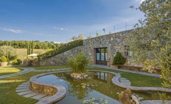 a large , well - maintained garden with a pond in the center is surrounded by stone walls and trees at Arco