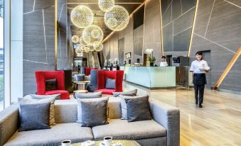 a modern hotel lobby with multiple couches , chairs , and tables , as well as a reception desk at Novotel Bangkok Impact