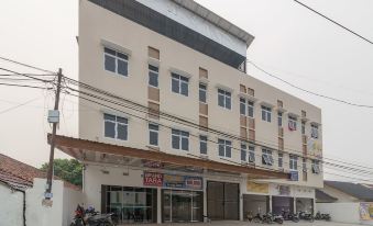 a modern building with multiple floors , balconies , and signage , as well as various motorcycles parked outside on the street at RedDoorz Plus Near Uin Raden Fatah Palembang