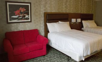 a hotel room with a red couch , white bed , and framed picture on the wall at Ramada by Wyndham Jacksons Point