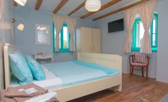 a bedroom with a large bed , white dresser , and blue walls , along with wooden beams and blue curtains at Villa Mare