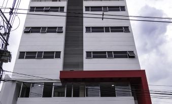 a tall white building with a red roof , situated in front of a cloudy sky at Hotel Perlatto