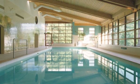 an indoor swimming pool with a large window , surrounded by windows that provide natural light at Denham Grove