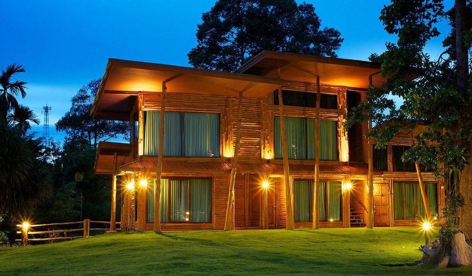 a modern wooden house with large windows and lit up by lights at night , surrounded by trees at Blues River Resort