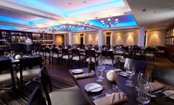 a large , well - lit dining room with multiple tables and chairs set for a formal dinner at Lancaster House Hotel