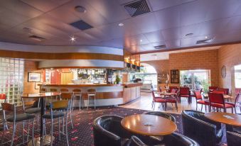 a modern restaurant with a bar area , where several people are seated and enjoying their meals at Windmill Motel and Events Centre