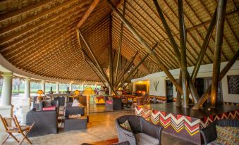 a large , open room with a high ceiling and wooden beams is filled with comfortable seating at Hotel Punta Teonoste