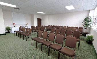 a conference room with rows of brown chairs arranged in a semicircle , and a projector on the wall at Riverview Inn