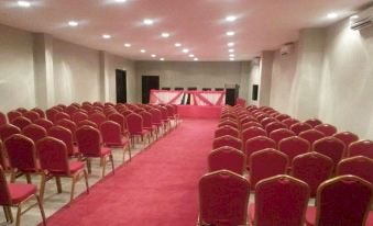 a large conference room with rows of red chairs and a stage at the end at Hotel Oceano