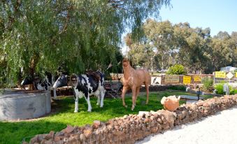 a horse and two cows are standing in a grassy area with trees and rocks at Little River Bed and Breakfast