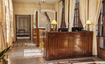 a hotel lobby with a wooden reception desk and chairs , creating a warm and inviting atmosphere at Hotel Villa Cornér Della Regina