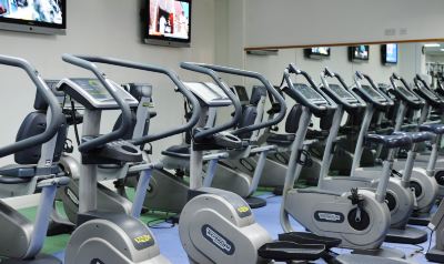 a room filled with exercise equipment , including treadmills , ellipticals , and stationary bikes , in a gym setting at Village Hotel Liverpool