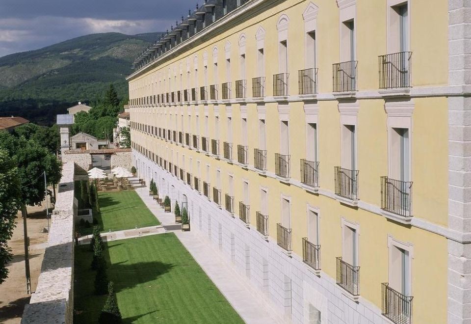 a large , modern building with multiple balconies and a green lawn in front of it at Parador de La Granja