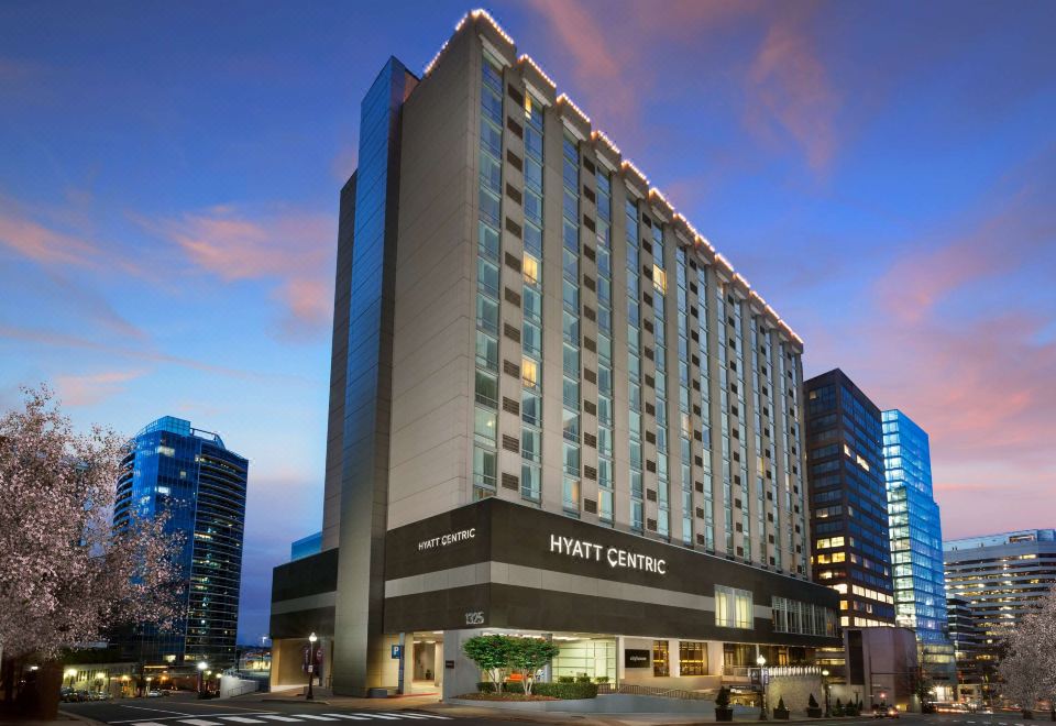 a hyatt centric hotel building in the middle of a city street , surrounded by buildings and cars at Hyatt Centric Arlington