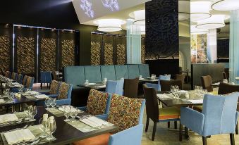 The restaurant features a spacious dining room with tables and chairs arranged in the center, ideal for hosting business luncheons at Remis Hotel