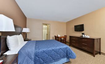 The bedroom is furnished with a large bed, desk, and chair, with the television positioned on top at Rodeway Inn