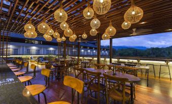 a modern restaurant with wooden tables and chairs , hanging lights , and a view of the outdoors at Plataran Heritage Borobudur Hotel