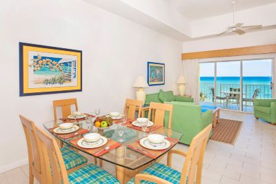 a dining room with a glass table set for a meal , surrounded by chairs and a couch at Wyndham Reef Resort Grand Cayman