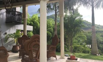 a porch with two wicker chairs , a fire pit , and a view of the mountains at Hacienda Tres Casitas