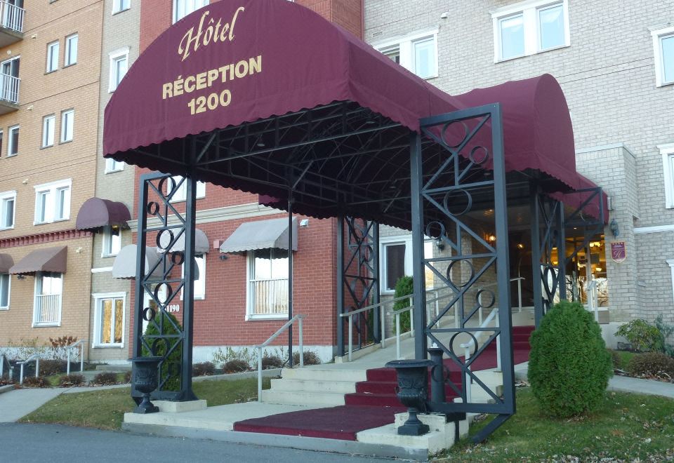 "a hotel entrance with a red canopy and stairs leading up to it , under the sign "" reception 1 2 0 0 .""." at Hotel Verso