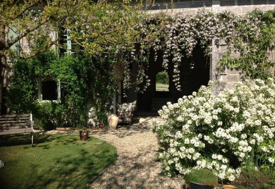 a beautiful garden with a stone path leading to a building , surrounded by lush greenery and white flowers at Deer House