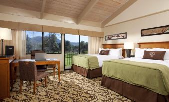 a hotel room with two beds , a desk , and a laptop , all set against a backdrop of mountains at Singing Hills Golf Resort