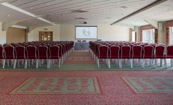 a conference room with rows of chairs arranged in a semicircle , and a projector on the wall at Greetham Valley