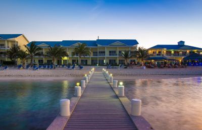 a dock extending into a body of water , with a building in the background and several lounge chairs placed around it at Wyndham Reef Resort Grand Cayman