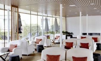 a modern lounge area with white couches and chairs , along with large windows offering views of trees outside at Scandic the Reef